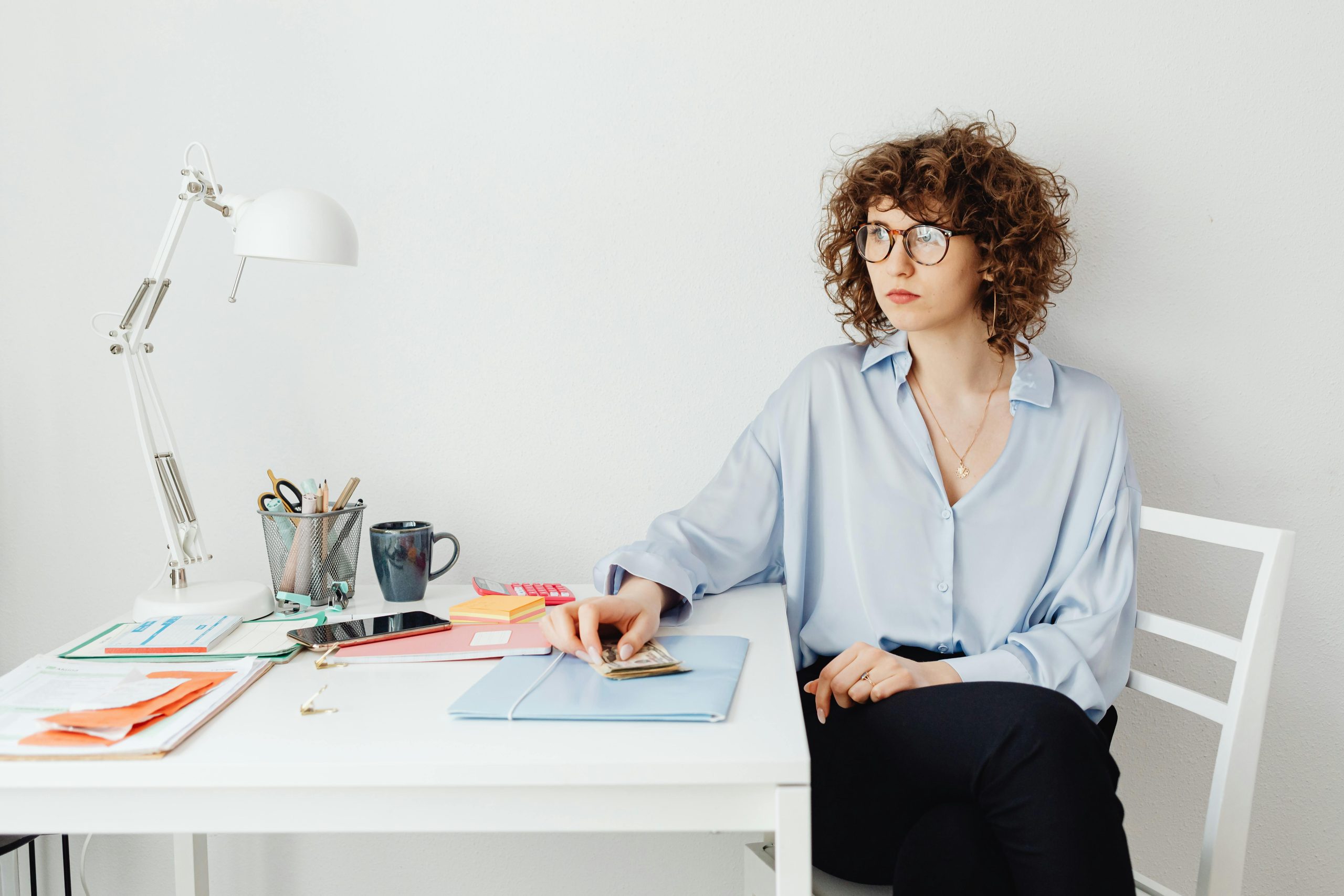 lazy budget method | woman looking tired sitting in front of table with papers and bills